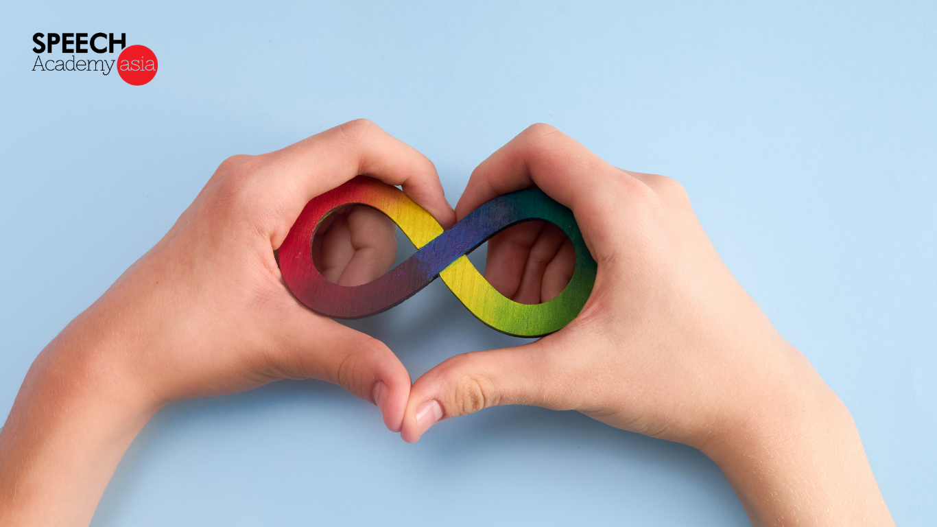 Hand forming a heart shape around a colorful infinity symbol for autism awareness.